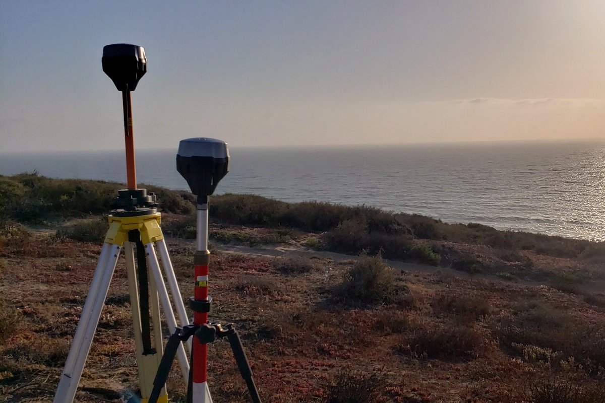 Equipos GNSS en estación base sobre lomerío con vista al mar